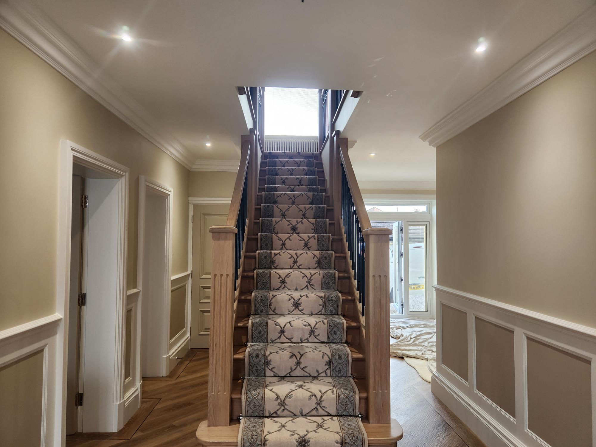 Grand entrance hallway with oak staircase and white wall panelling