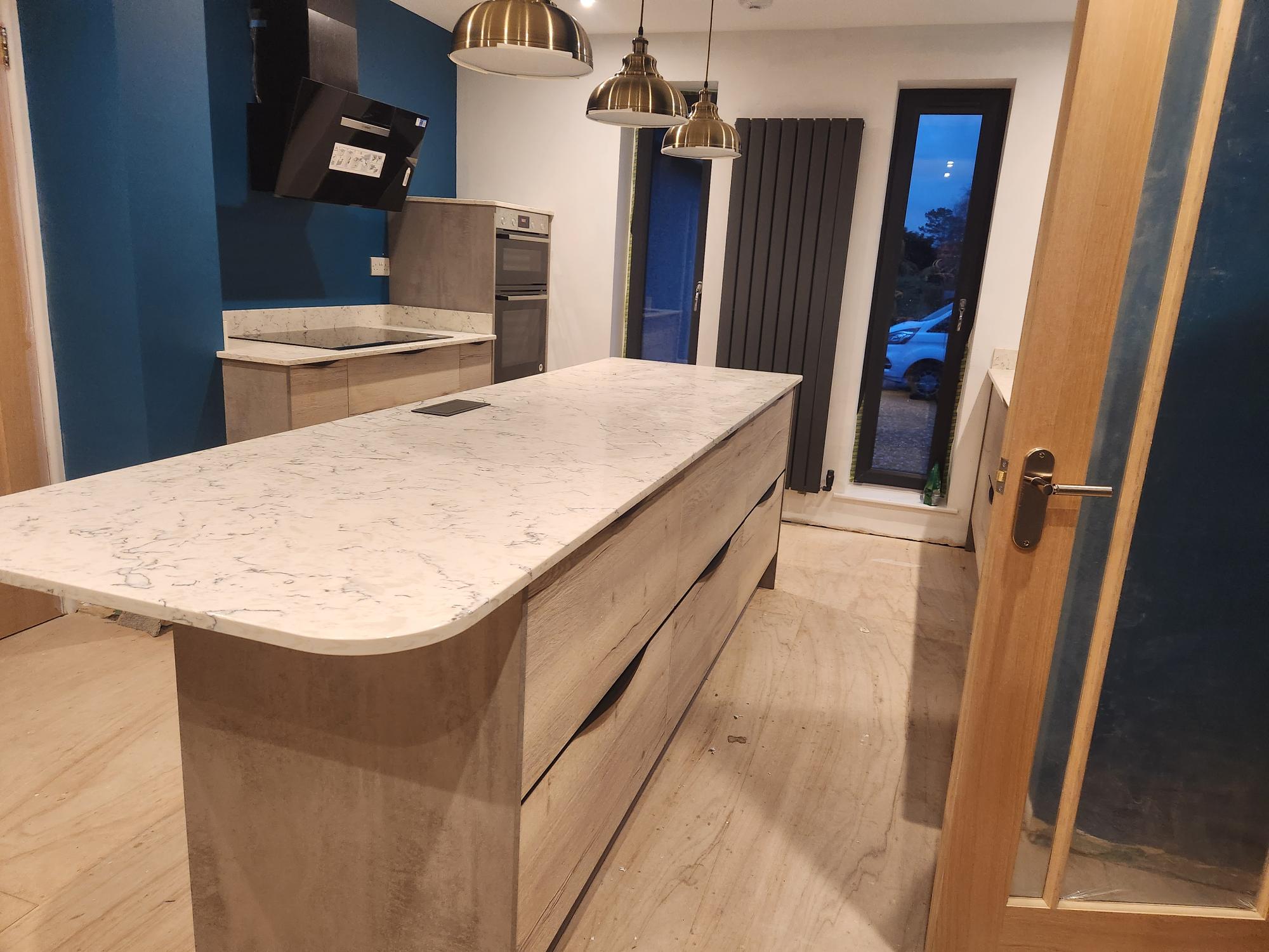 Kitchen island with marble worktop and brass pendant lighting
