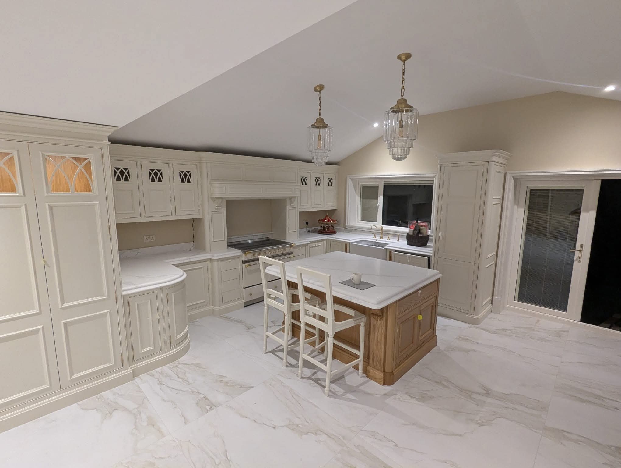 Traditional kitchen with bar stools, curved units and crystal pendant lights