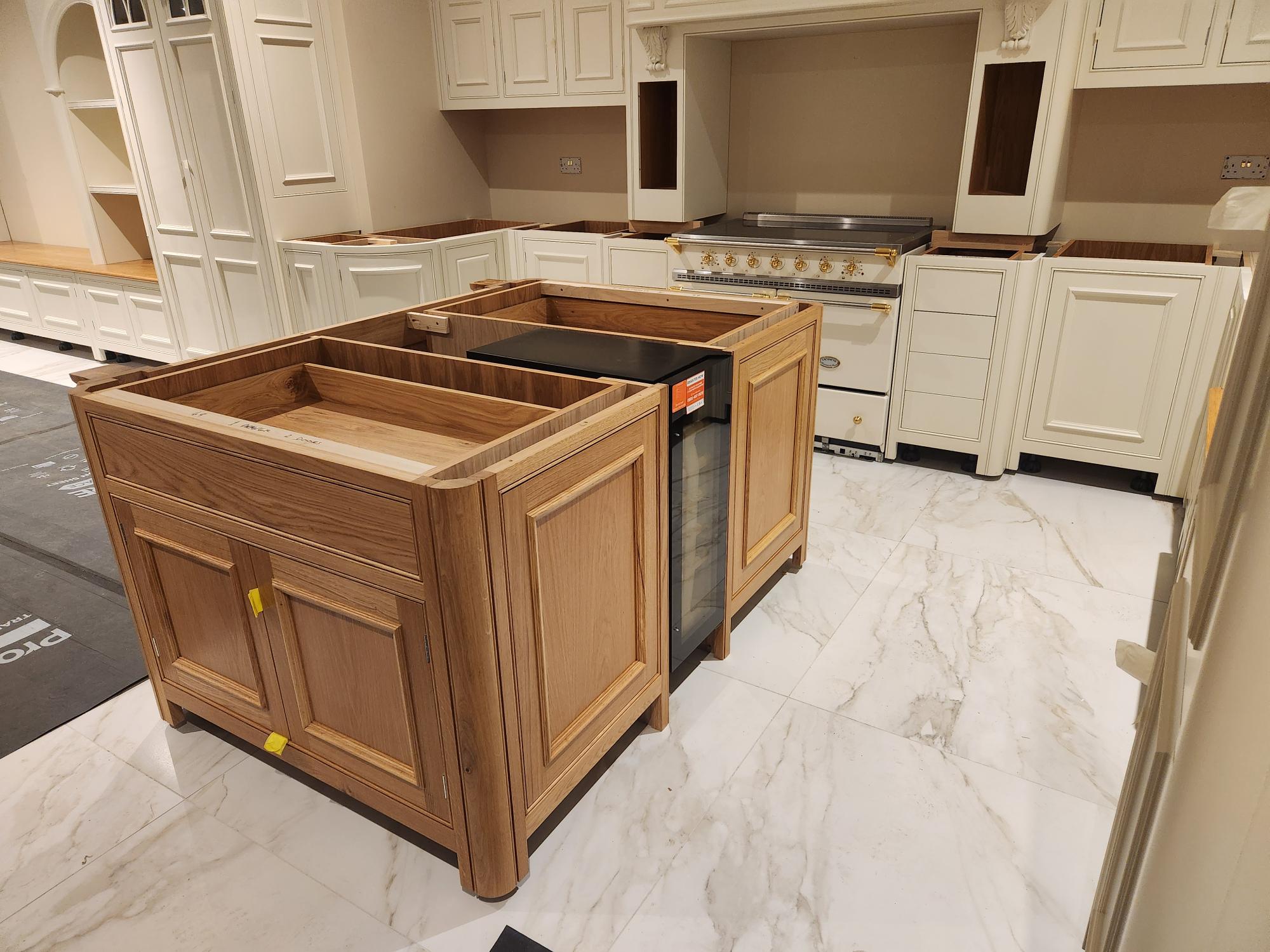 Oak island with wine fridge and gothic-style cream wall cabinets
