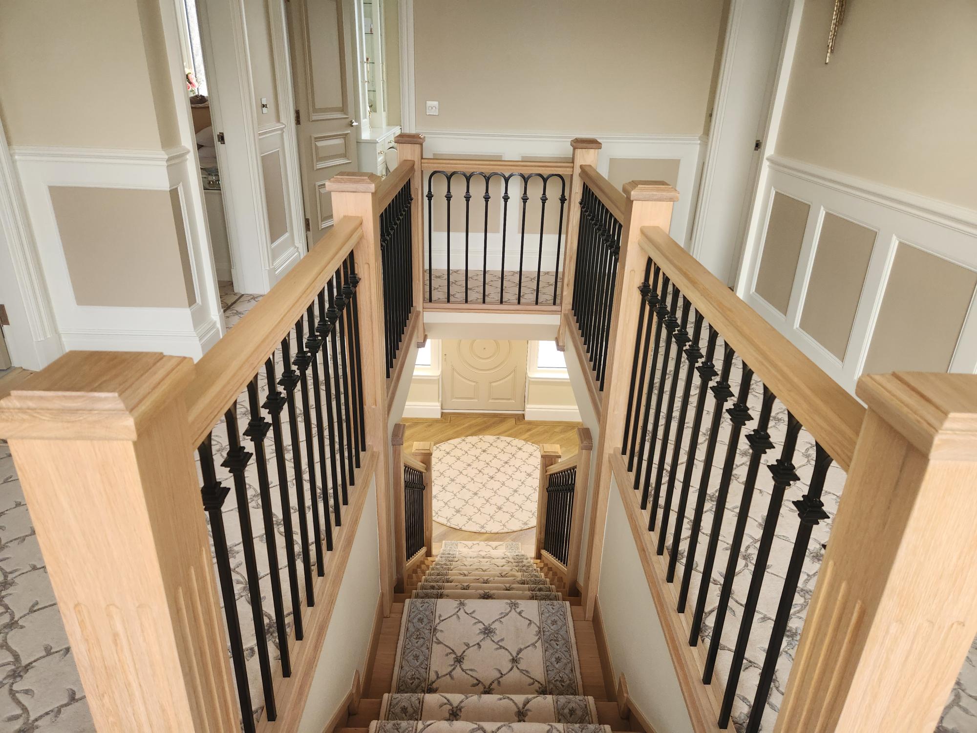 Split-level oak staircase with black iron spindles and white panelling